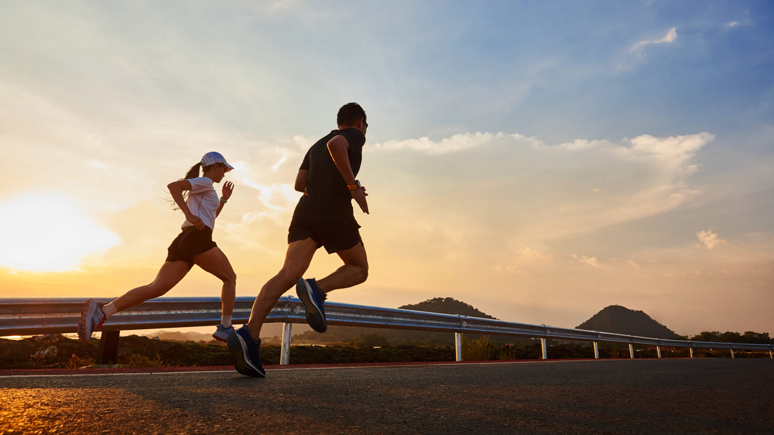 Two men and women jogging in casual wear jogging on the road at sunset.